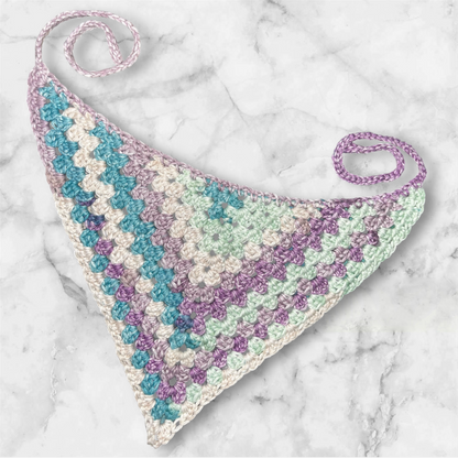 crochet granny bandana in multicolor of teal blue, sea foam green, cream, and a lavender shade, on a marble background